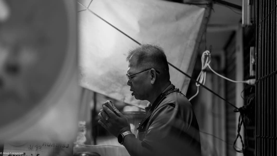 A man offers prayers before opening his shop for the day in Chinatown, Bangkok.